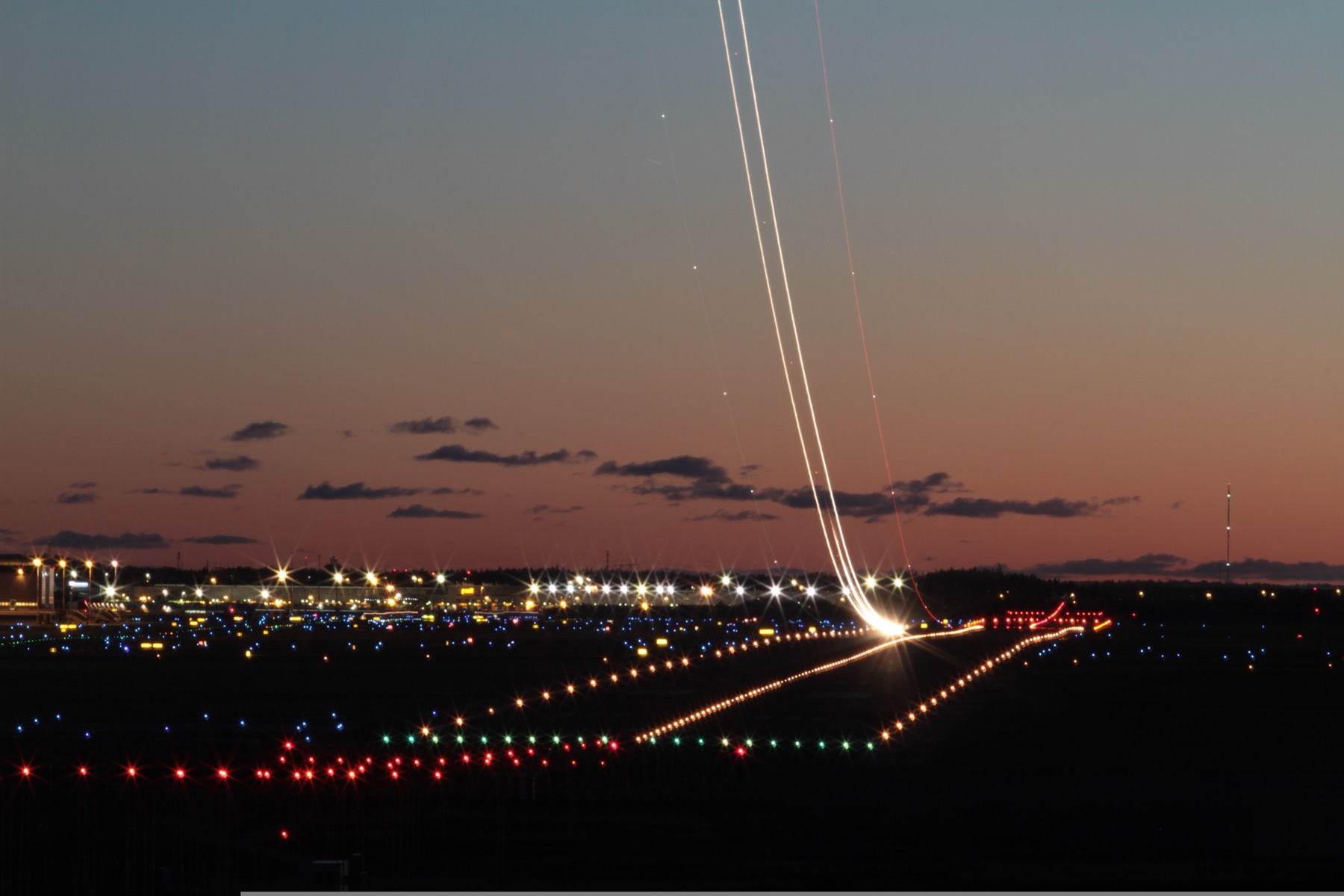 Long-exposure light trails of a departing aircraft over airfield ground lighting
